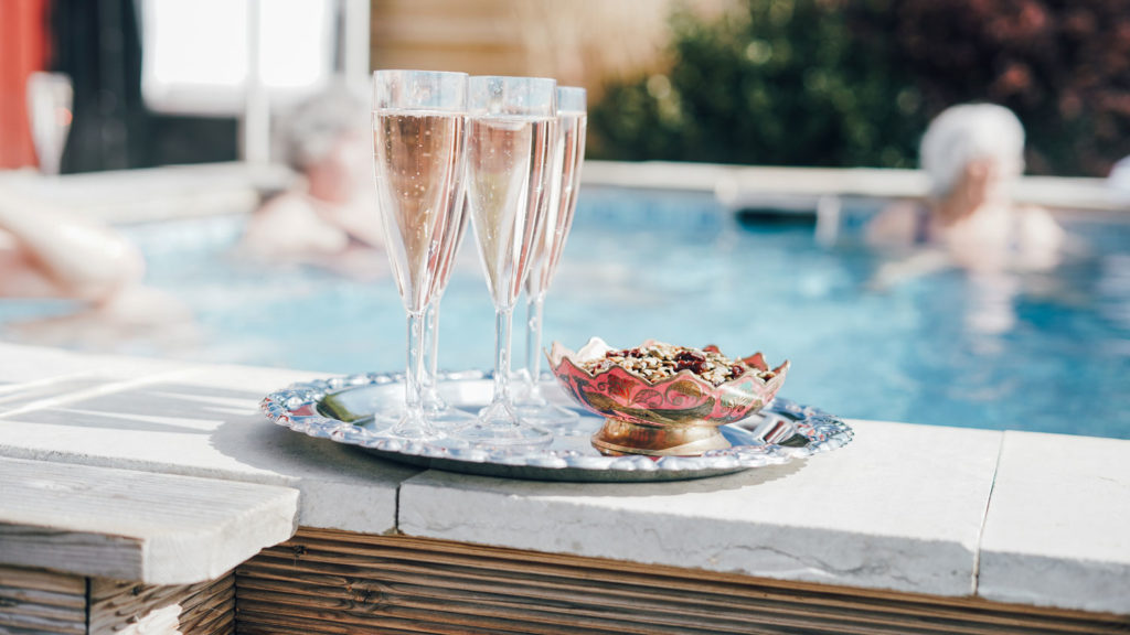 Bricka med champagneglas och tilltugg står på en poolkant