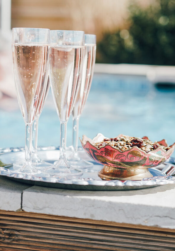 Bricka med champagneglas och tilltugg står på en poolkant